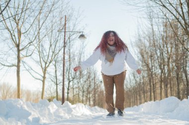 Smiling chubby redhead woman running in park in winter
