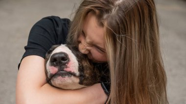 Beyaz kadın portresi açık havada köpeğine sarılıyor.
