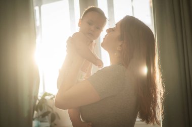 Beyaz bir kadın yeni doğmuş oğlunu nazikçe kaldırır.