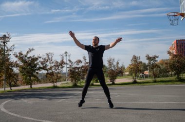 Sakallı adam spor sahasında koşmadan önce ısınıyor.