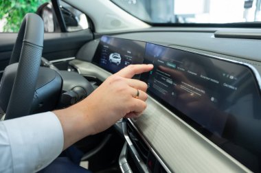 Modern bir arabanın torpido gözüne yakın çekim yapan bir adam.