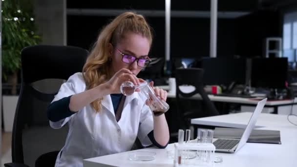 実験室での実験を行っている医療ガウンの白人女性 — ストック動画