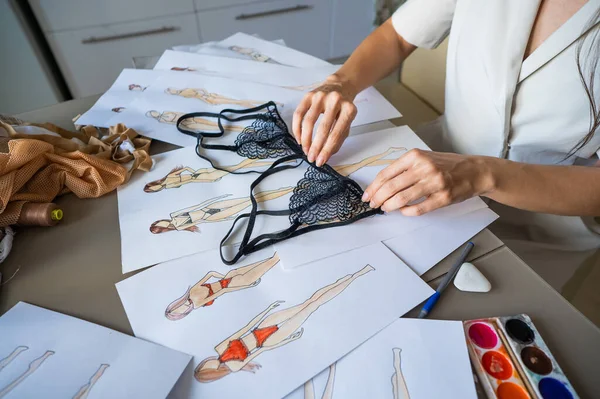 Faceless woman draws underwear sketches. Close-up of fashion designers hands with lace bra