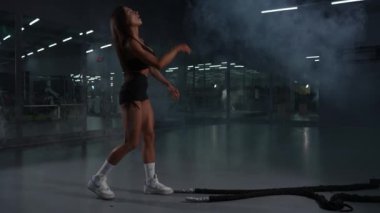 Bir kadın egzersizi iplerle bitirir. Spor salonunda tur eğitimi var. Yavaş çekim. 