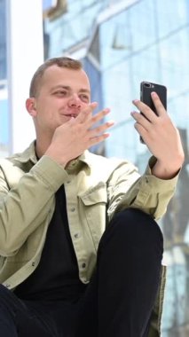 Beyaz adam açık havada akıllı telefondan işaret dili konuşuyordu. Dikey video