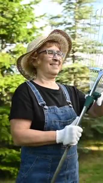 一个戴着帽子和工作服的老年妇女的画像是拿着一个园艺工具 垂直视频360度 — 图库视频影像