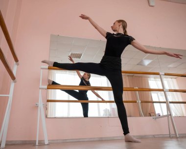 Kafkasyalı sarışın kadın sınıfta bale çalışıyor. Balerin barda prova yapıyor.