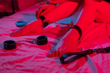 Neon-mavi ışıkta zincirlenmiş kadın bacaklarının yakın çekimi. BDSM konsepti