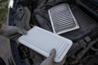 Araba motorundaki hava filtresini değiştiriyor.