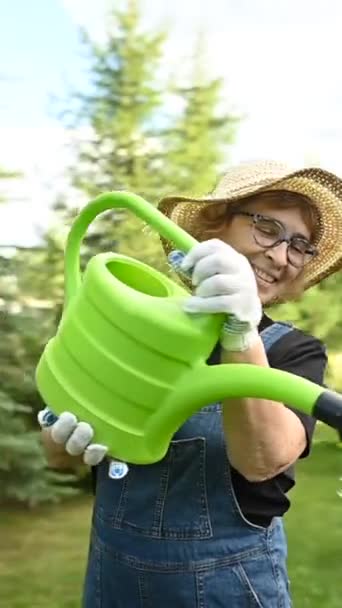 视频360度一位老妇人正在用水壶浇灌花园 垂直录像 — 图库视频影像