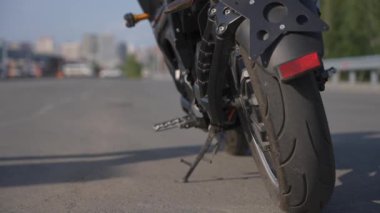 Adamın biri elektrikli motosiklete biniyor, amuda kalkıyor ve uzaklaşıyor.