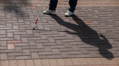 Yüzü olmayan kör bir kadın bastonuyla sokakta yürüyor.