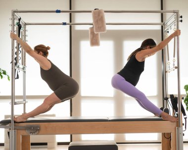 İki hamile kadın Cadillac 'ta pilates yapıyor.