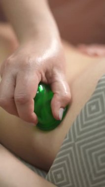 Masöz, müşterilere sırt masajı yaparken vakumlu plastik kutular kullanır. Dikey video
