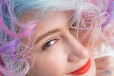 Çok renkli saçlı, kıvırcık beyaz bir kadının yakın plan portresi. Saç stilleri için model.