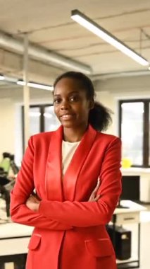 Ofiste kırmızı takım elbiseli Afrikalı genç bir kadının portresi. Dikey video 360 derece