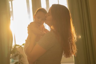 Beyaz bir kadın yeni doğmuş oğlunu nazikçe kaldırır.