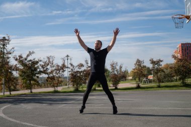 Sakallı adam spor sahasında koşmadan önce ısınıyor.