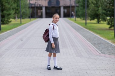 Beyaz kız öğrenci portresi. Üniformalı ve sırt çantalı.