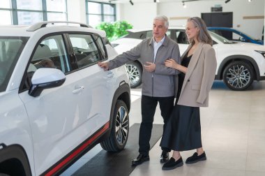 Yaşlı beyaz bir çift araba galerisinde yeni bir araba seçiyor.