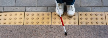 Kadın ayağı, baston ve dokunsal fayansların yakın çekimi. Geniş Ekran