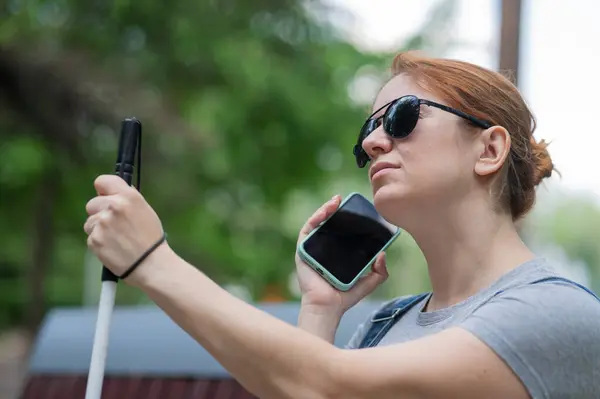 stock image A blind woman sits on a bench and communicates on a smartphone