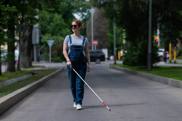 Blind pregnant woman walking down the street with a cane