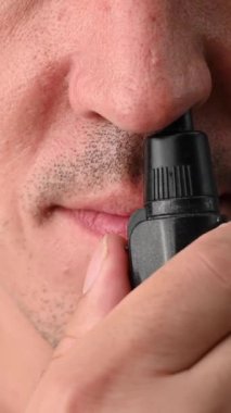 Bir adam burun kıllarını bir cep budayıcı ile kesiyor. Dikey video