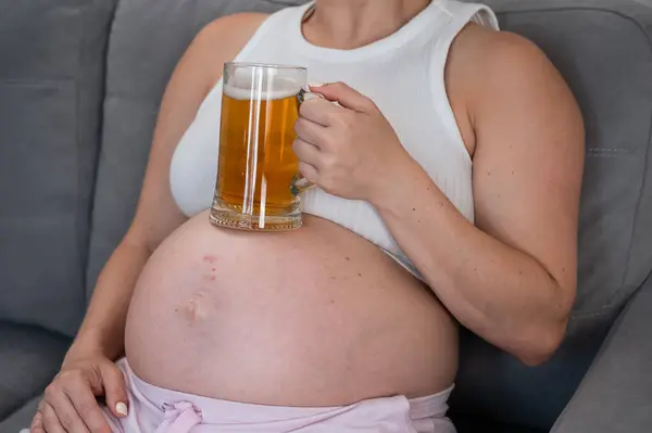 Uma Mulher Grávida Sem Rosto Senta Sofá Segura Copo Cerveja — Fotografia de Stock