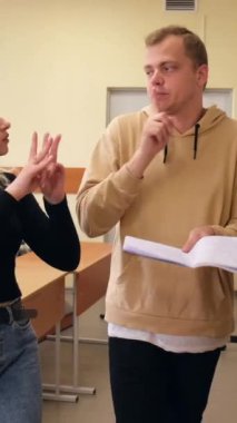 İki kız ve bir erkek işaret diliyle konuşuyorlar. Üç sağır öğrenci bir üniversite sınıfında sohbet ediyorlar. Dikey video