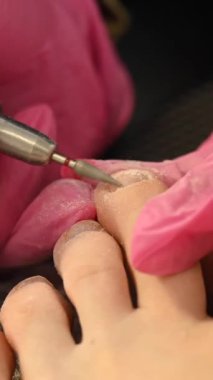 Usta müşteriye donanım pedikürü yapıyor. Dikey video