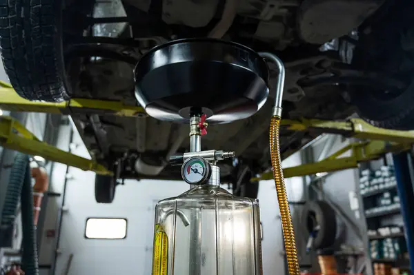 在汽车发动机中更换机油的过程 从电梯上的汽车中排出旧的深色废油 — 图库照片