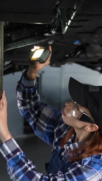 Female Mechanic Inspects Lifted Car Girl Mans Work Vertical Video — Stock Video