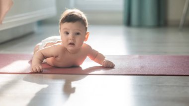 Sevimli küçük çocuk kollarının üzerinde yerde yatıyor.