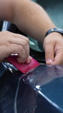 Araba servisindeki usta arabaya zırh filmi uyguluyor. Dikey video