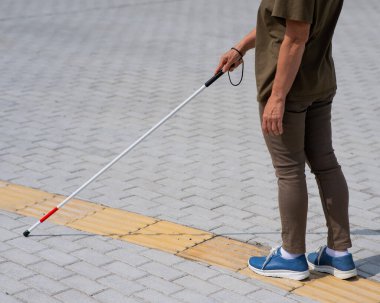 Yaşlı, kör, bastonlu, dokunmatik bir kadının bacaklarına yakın çekim.