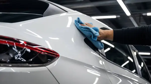 机械师用微纤维布擦拭一辆白色汽车的车身 — 图库照片