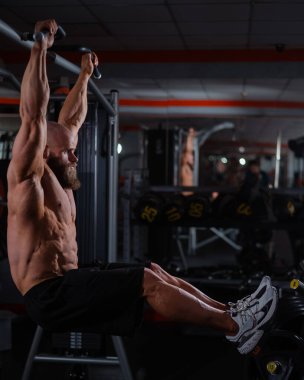 Kafkas bir adam yatay bir çubuğa asılır ve bacaklarını kaldırır. Dikey fotoğraf