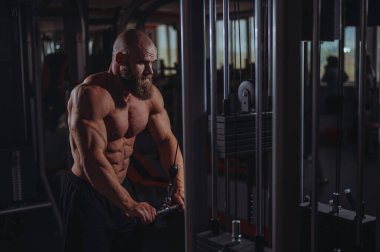 Kel Kafkas vücut geliştirici kabloyla ağır triseps egzersizleri yapıyor.