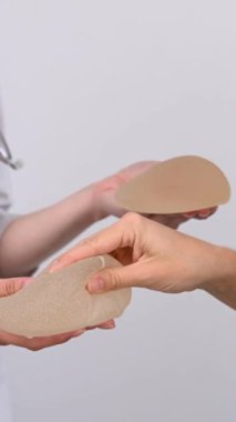 Beyaz kadın ve estetik cerrah göğüs implantlarını seçiyor. Dikey video