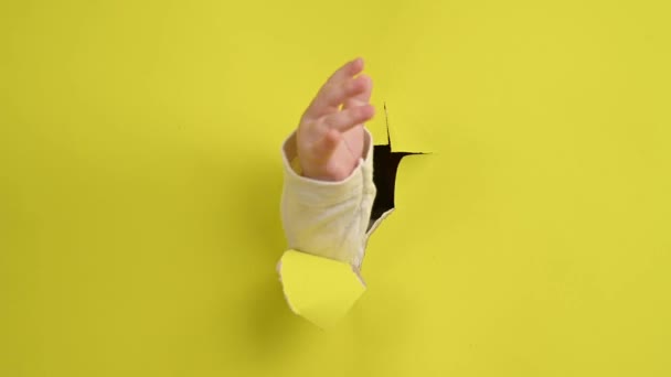 Babys Χέρι Ξεχωρίζει Μέσα Από Μια Τρύπα Ένα Κίτρινο Φόντο — Αρχείο Βίντεο