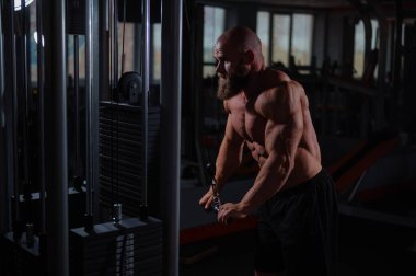 Kel Kafkas vücut geliştirici kabloyla ağır triseps egzersizleri yapıyor.