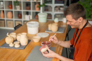 Potter seramik tabakları fırçayla boyar.