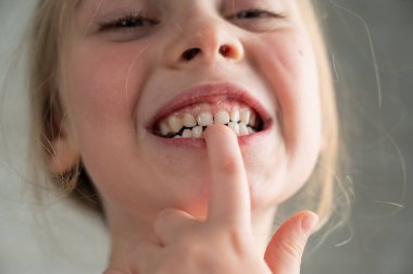 Çikolataya bulanmış şirin küçük bir kız kanepede yatarken kurabiye yiyor.