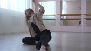 Beyaz kadın bale sınıfında yerde çağdaş dans ediyor.