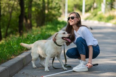 Dışarıda yürürken rehber köpeğe sarılan kör genç bir kadın.