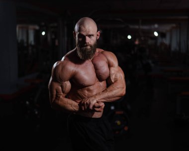 Spor salonunda poz veren beyaz kel adam.