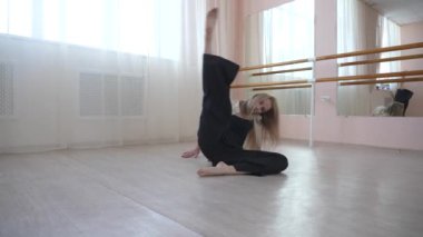 Beyaz kadın bale sınıfında yerde çağdaş dans ediyor.