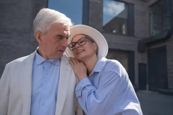 帽子とメガネを被った女性は 後ろから白いジャケットを着た老人を抱きしめる 成熟した人々のロマンチックな関係 — ストック写真