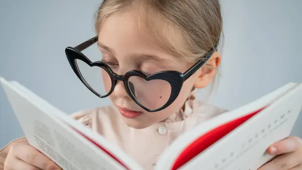 Kalp Şeklinde Gözlüklerle Kitap Okuyan Küçük Bir Kızın Portresi — Stok fotoğraf